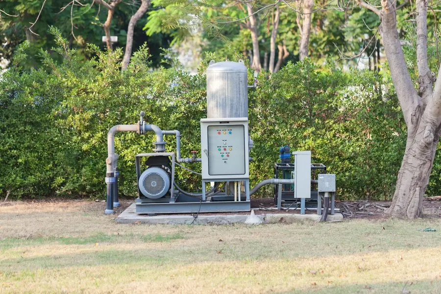 Water well pump station with pressure tank, motor and control panel on a concrete pad