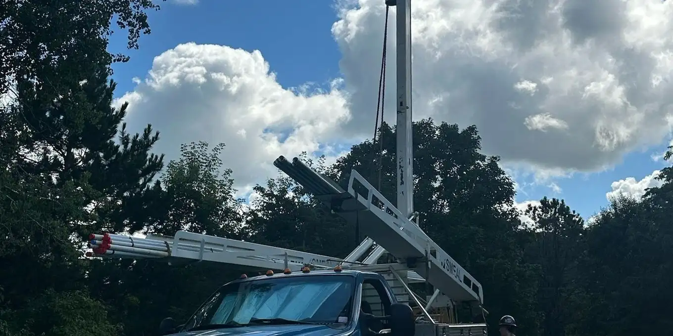 Lauren McCullough service truck with its drilling derrick raised against a blue sky