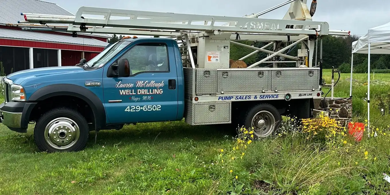 Lauren McCullough well service truck parked in a field beside a farm building