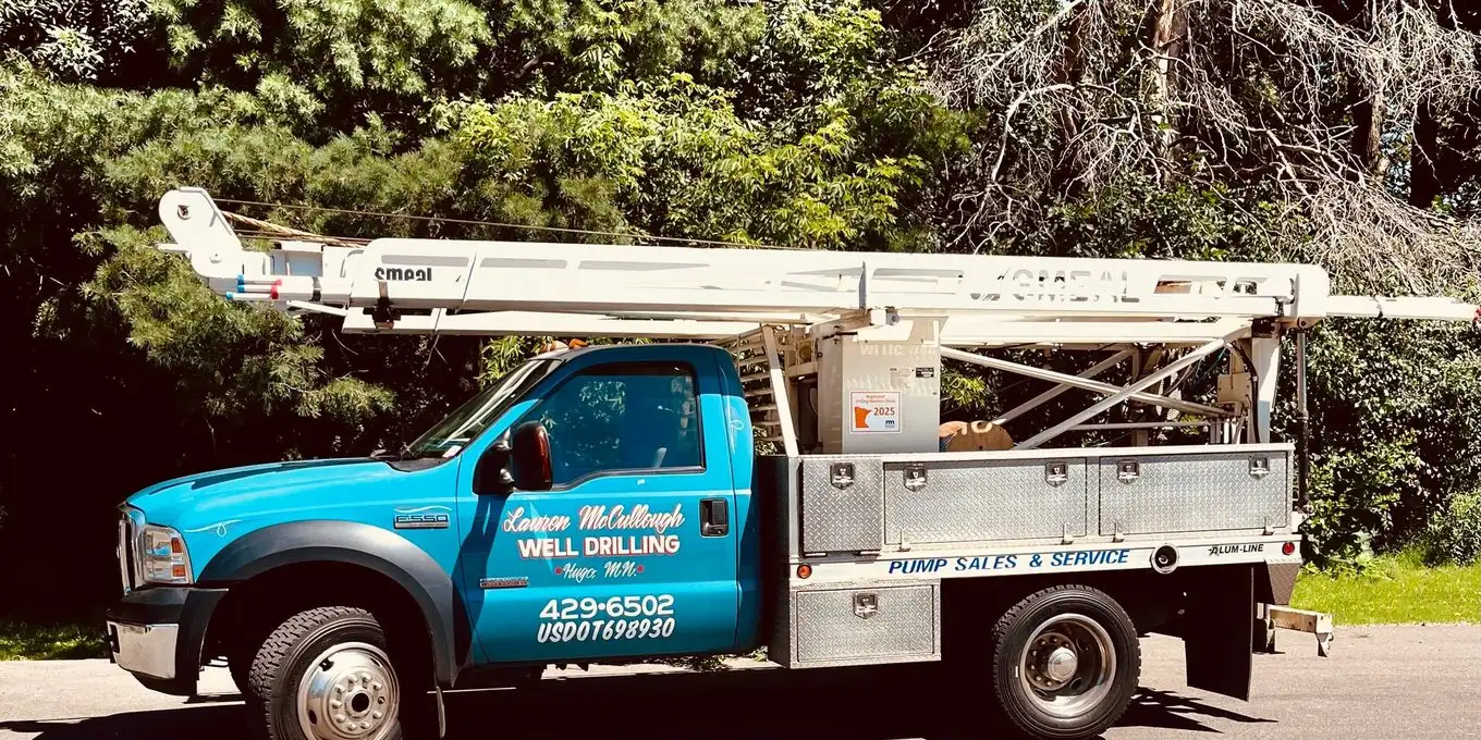 Lauren McCullough well service truck with its derrick folded down, parked on a tree-lined road